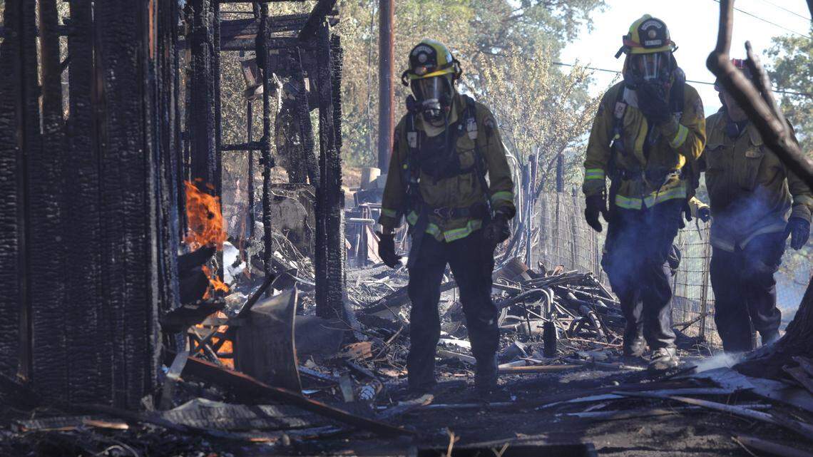 Firefighters examine a broken gas line at a house that was destroyed on Almond Street in Paso Robles.