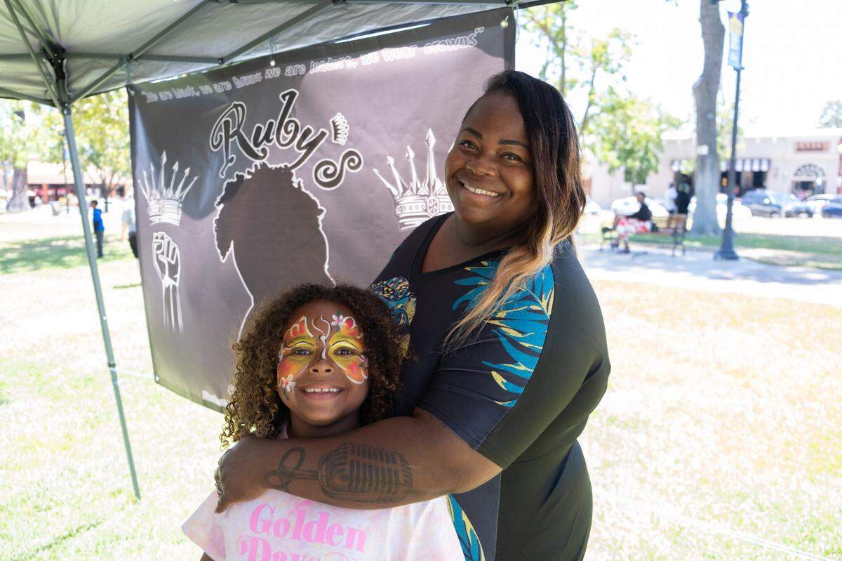 Ashley Brown, right, and her daughter, Jade, smile at their booth for Ruby’s, an organization run by Brown that brings together Black and brown youth in SLO County, during the Juneteenth Jubilee in downtown Paso Robles on June 18, 2022. 