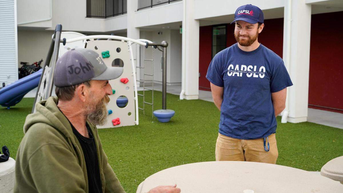 U.S. Marine Corps veteran Brian Brewer and Community Action Partnership of San Luis Obispo case worker Nathan Rubinoff talk in the courtyard of Broad Street Place, a People’s Self-Help Housing affordable housing complex, March 1, 2024.