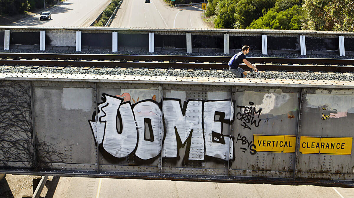 A cyclist rides past graffiti spray-painted on the Union Pacific railroad bridge near California Boulevard in San Luis Obispo.