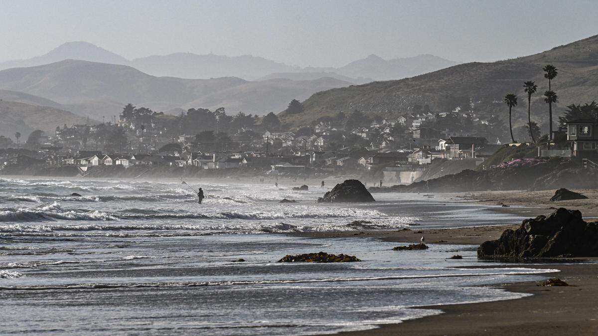 A person fishes in the surf in Cayucos in June 2024