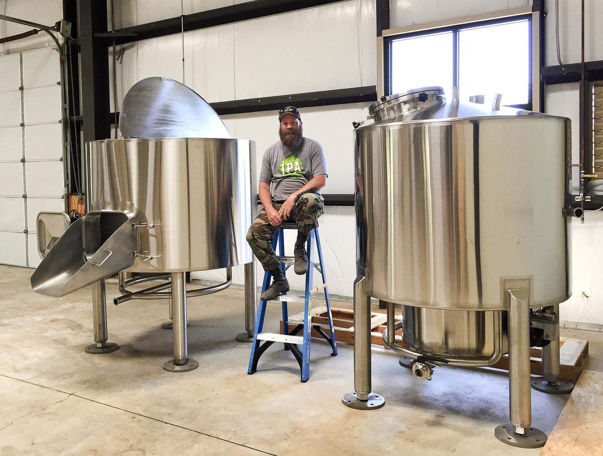 Chris Chambers, owner of Dunbar Brewing, sits between a mash/lauter tun and a kettle in his brewhouse at 22815 El Camino Real in Santa Margarita in 2015. The brewery is moving to Atascadero in the summer of 2019.