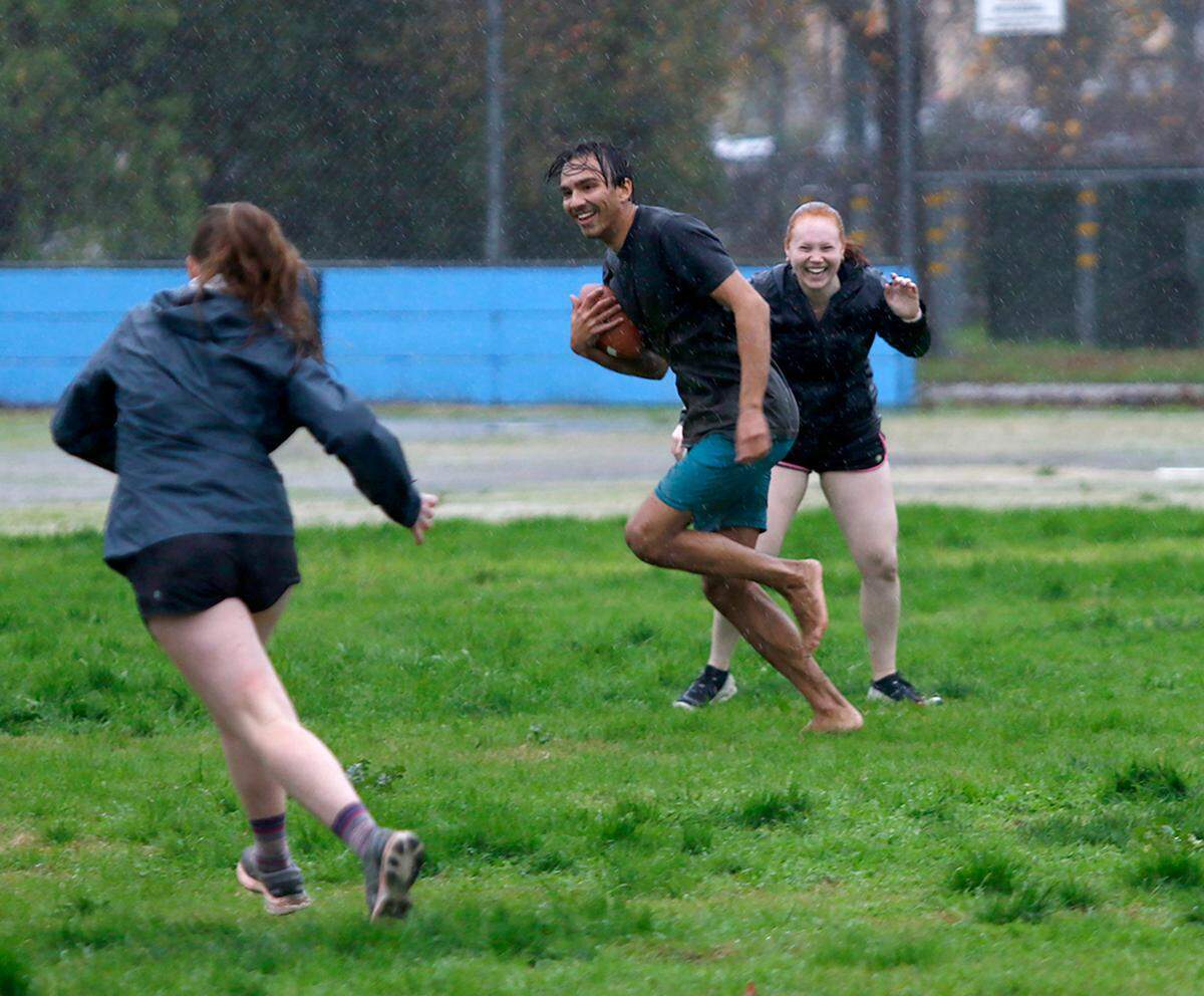 Cal Poly engineering students play football in the rain at the Pacific Beach High School baseball field in San Luis Obispo on Monday, Jan. 9, 2023. The university canceled classes because of the stormy weather.