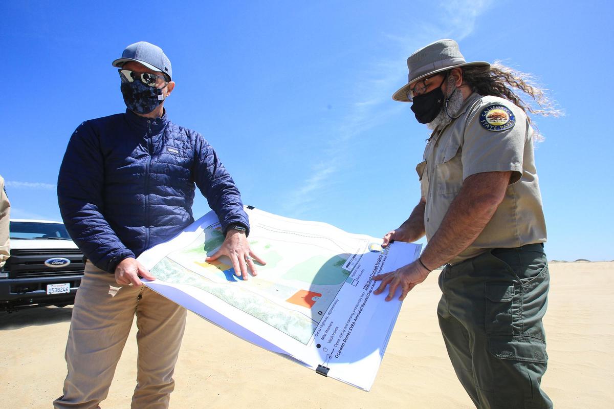 UCSB Professor Ian Walker, left, and Ronnie Glick, senior environmental scientist with California State Parks, right, show a map of the revegetation project in the foredunes to reduce air pollution from wind-driven sand.