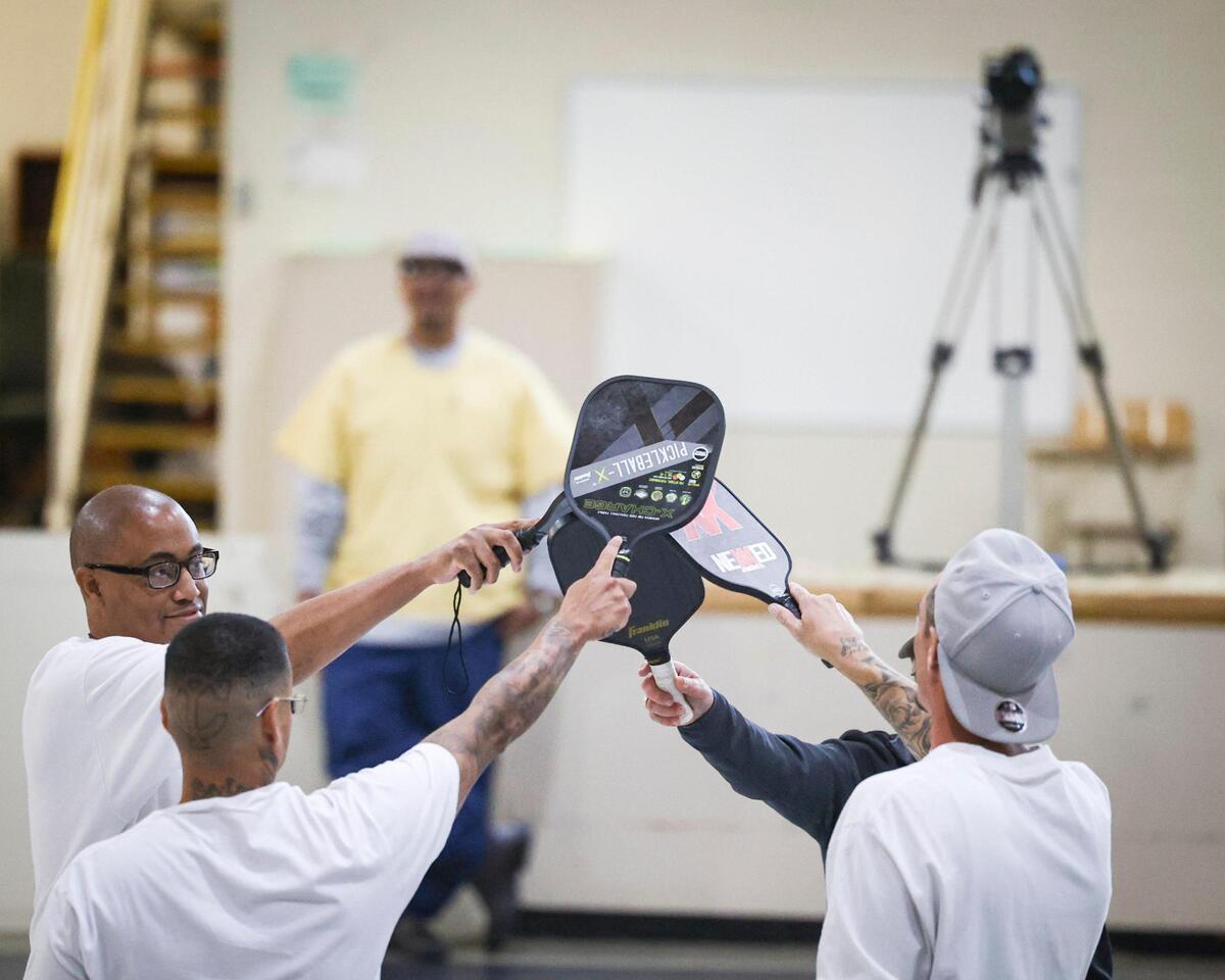 Pickleball coach Roger BelAir brings Californian Men’s Colony inmates together at the end of a match to raise paddles in a “group hug” as a sign of sportsmanship and respect, regardless of the outcome, during his visit to the prison on Nov. 12, 2024.
