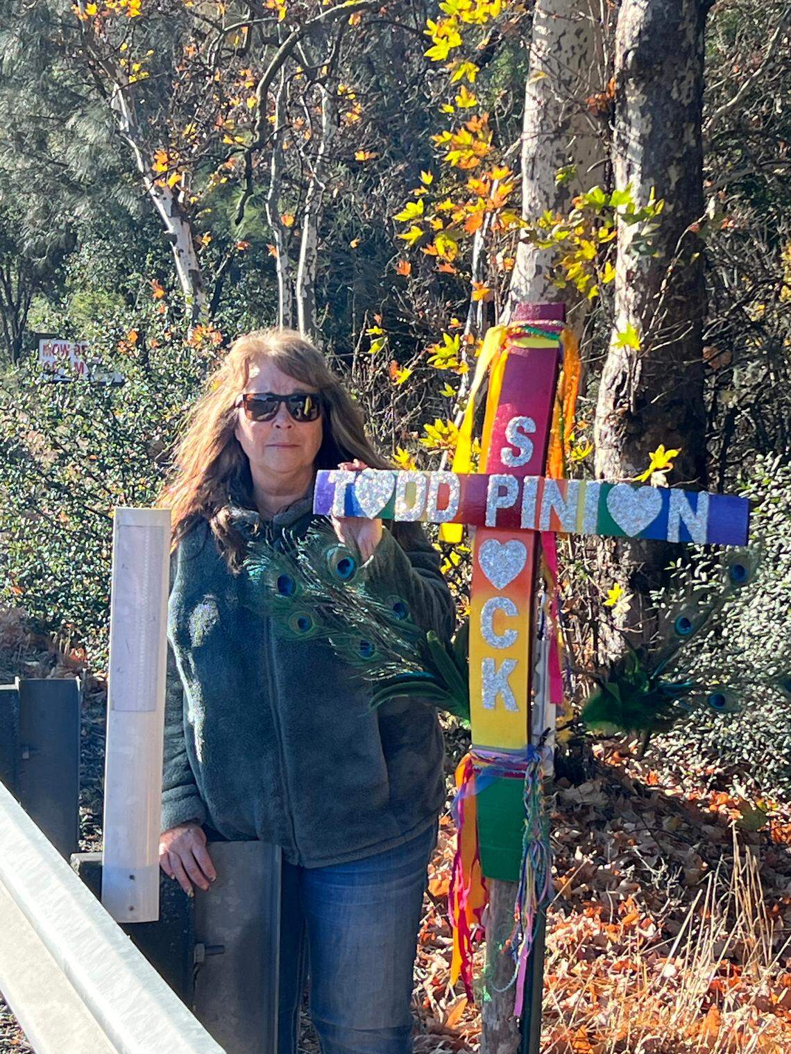 Melody Pinion poses next to the memorial at the beginning of Tassajara Creek Road on Dec. 17, 2024. Her son, Todd Pinion, was found murdered near the location on Nov. 3, 2024.
