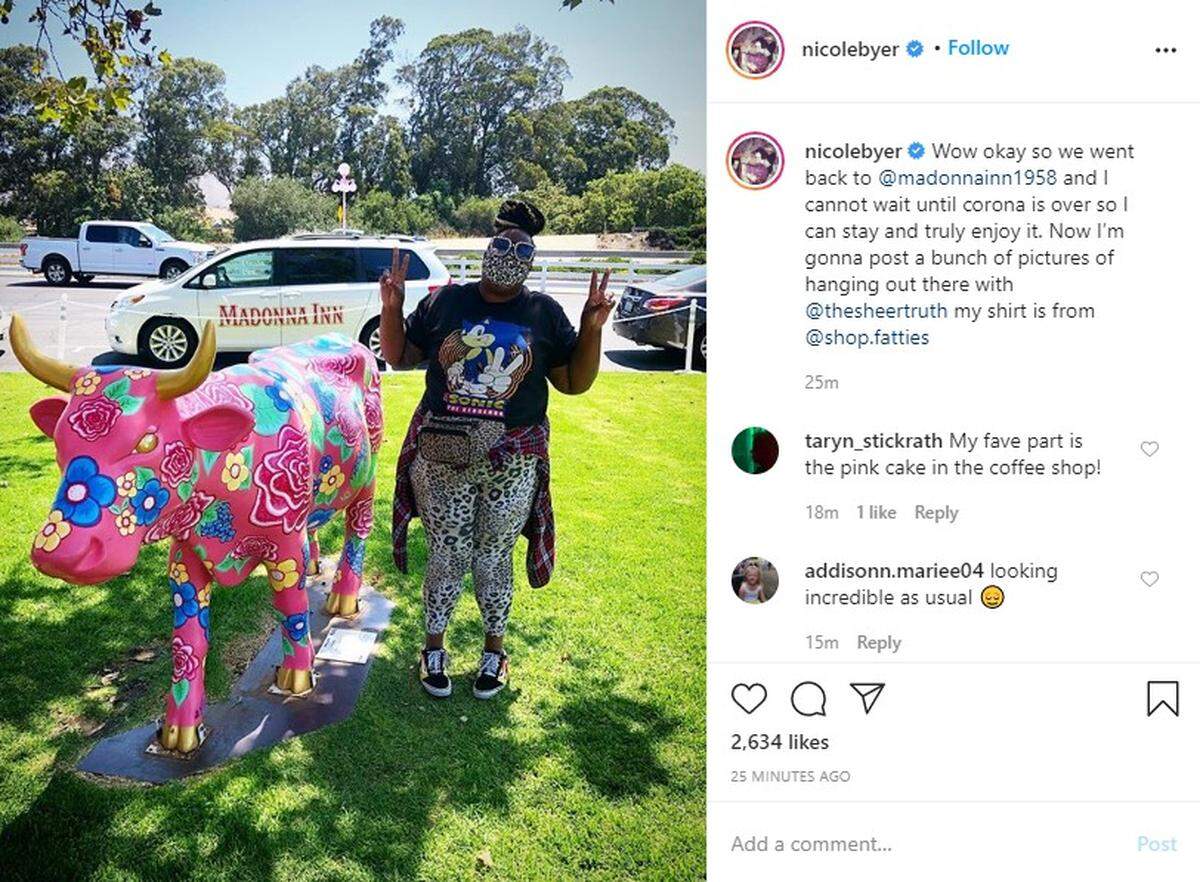 A mask-wearing Nicole Byer poses for a photo with a fiberglass cow at the Madonna Inn in San Luis Obispo.