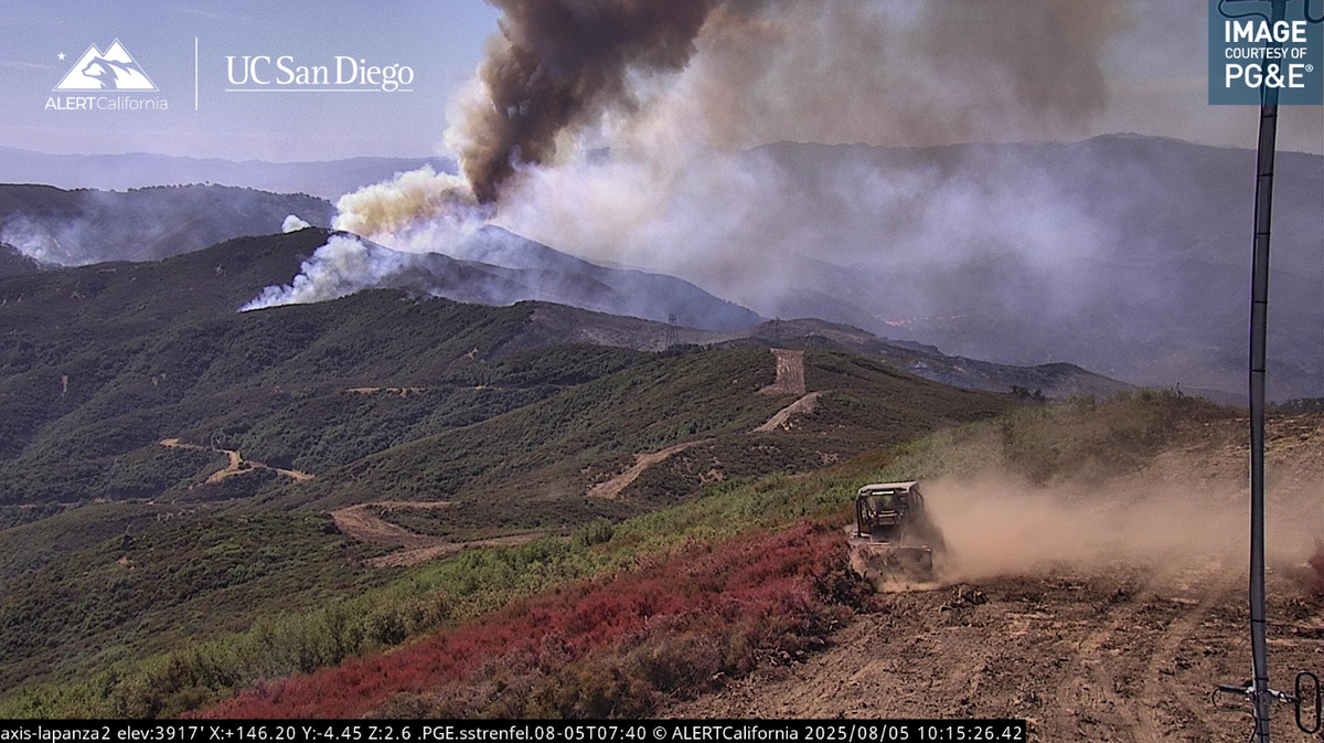 A bulldozer clears brush around ALERT California’s La Panza 2 camera as the Gifford Fire burns in the background on Tuesday, Aug. 5, 2025.