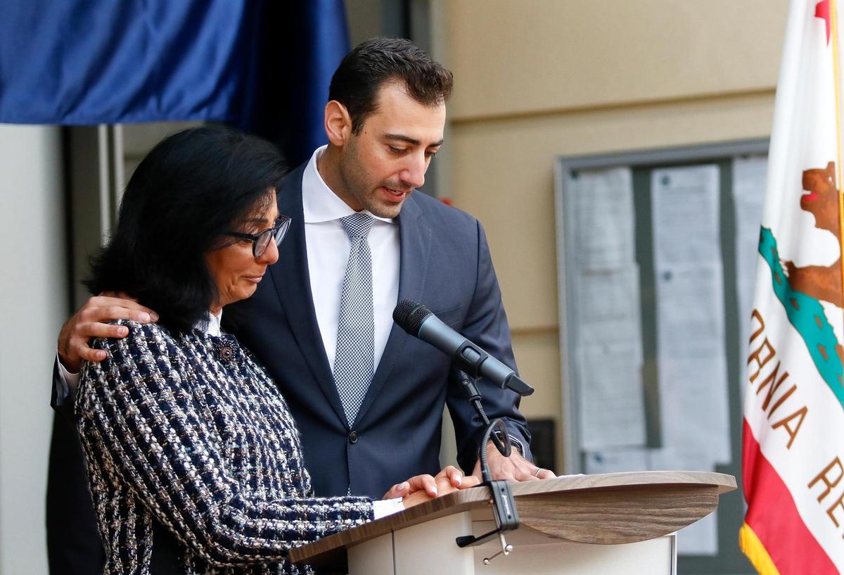 The new Katcho Achadjian Government Center sign was unveiled in a ceremony Friday, Oct. 20, 2023, in front of the former San Luis Obispo County Government Center. SLO County Supervisor John Peschong emceed the festivities. Achadjian’s wife Araxie, his daughter Nyri and son Hratch all spoke at the podium before Araxie pulled down a blue cloth revealing the new sign. Here, Araxie, teared up before her son stepped in.