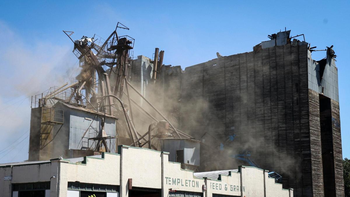Dust rises as the metal superstructure at the Templeton Feed & Grain building is pulled over by the guy wires that once supported it. Demolition of the landmark Templeton Feed & Grain building was underway on July 7, 2025. The historic building burned in a fire that sparked in the late night hours of July 4.