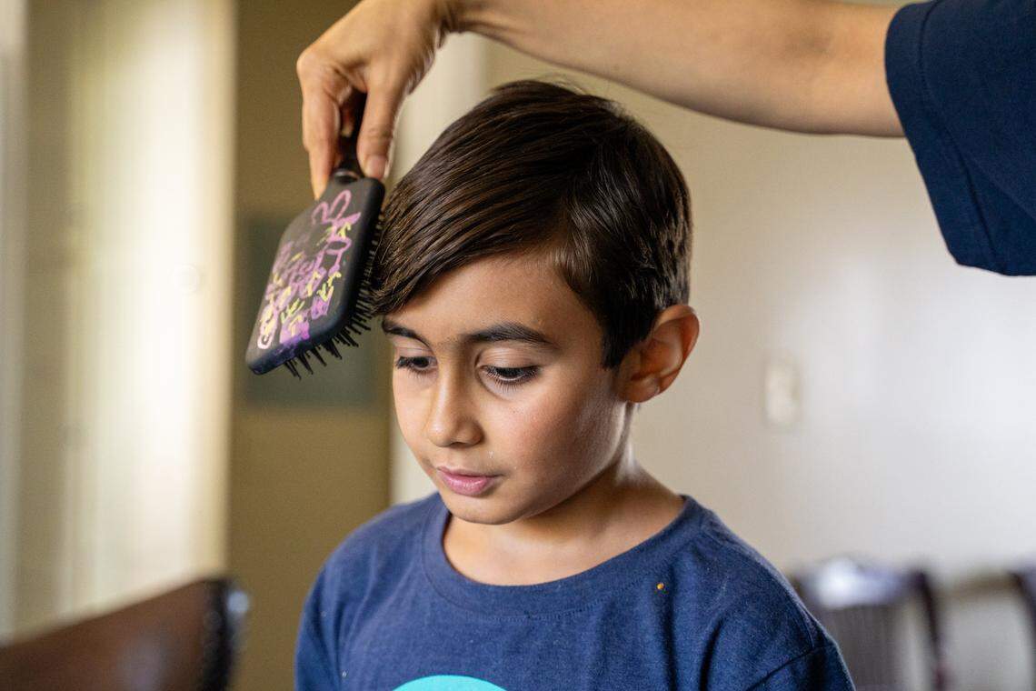 Parsa Rashvandmeli's mother Fatemeh Nayebloie brushes his hair before he practices piano on Saturday, Oct. 11, 2025. The family recieved music lessons this year at no cost through the Infinite Music program.