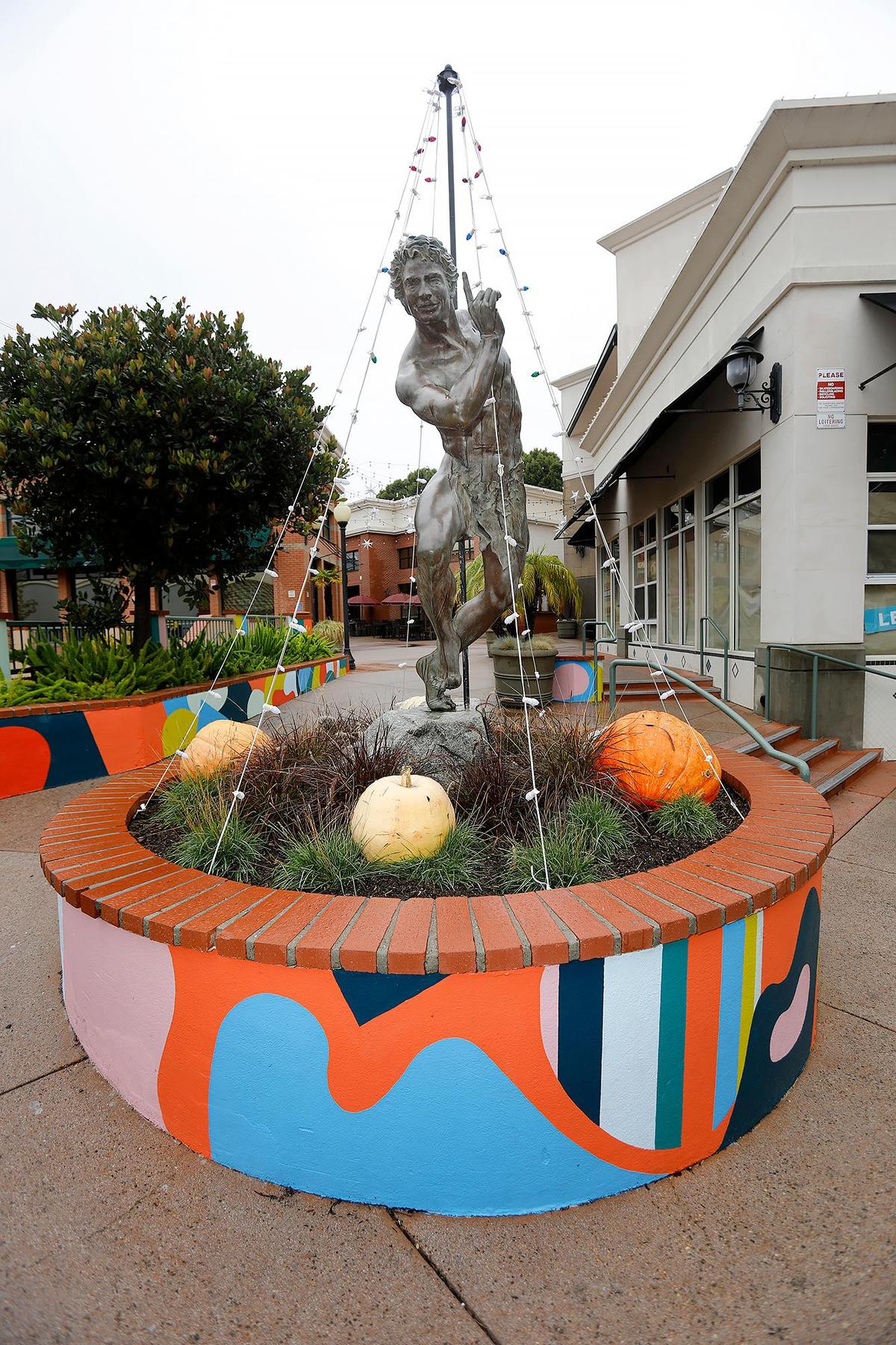 A large planter surrounding a statue of Puck has been transformed from a sedate tan to an eye-popping collage of color.
