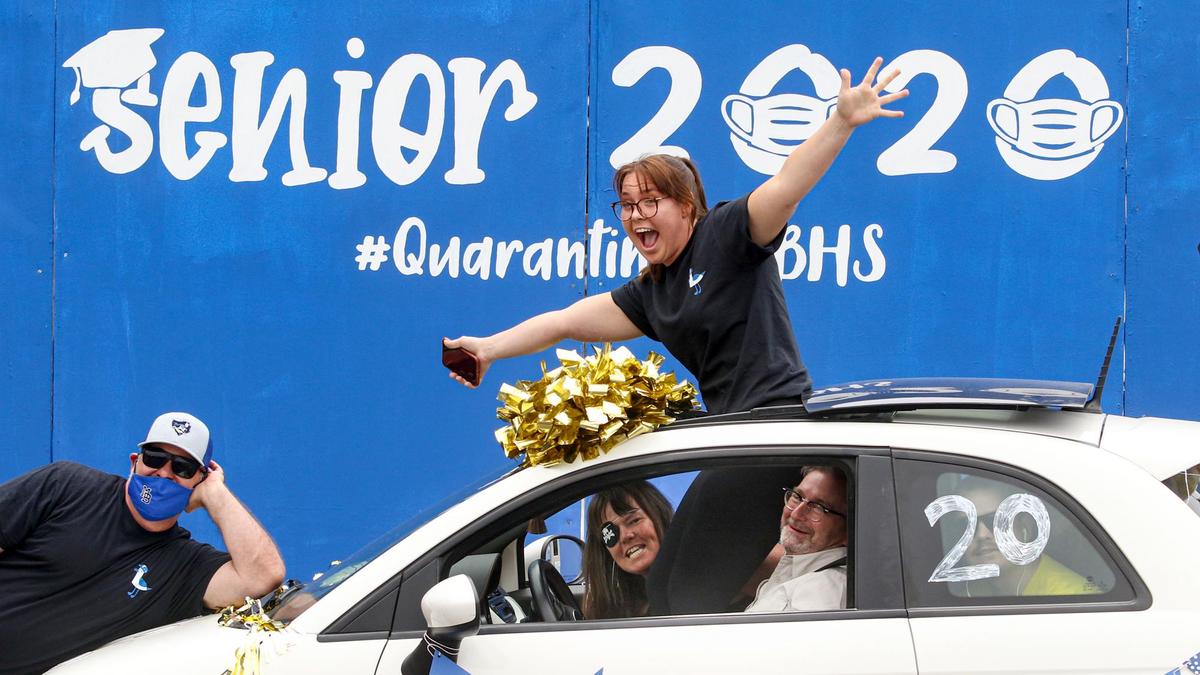 Morro Bay High School graduate Season Bryant celebrates while standing in the sunroof during a campus drive-through event on Thursday. At left, Principal Kyle Pruitt leans into the photo. Morro Bay is planning to hold its offical graduation ceremony in August.