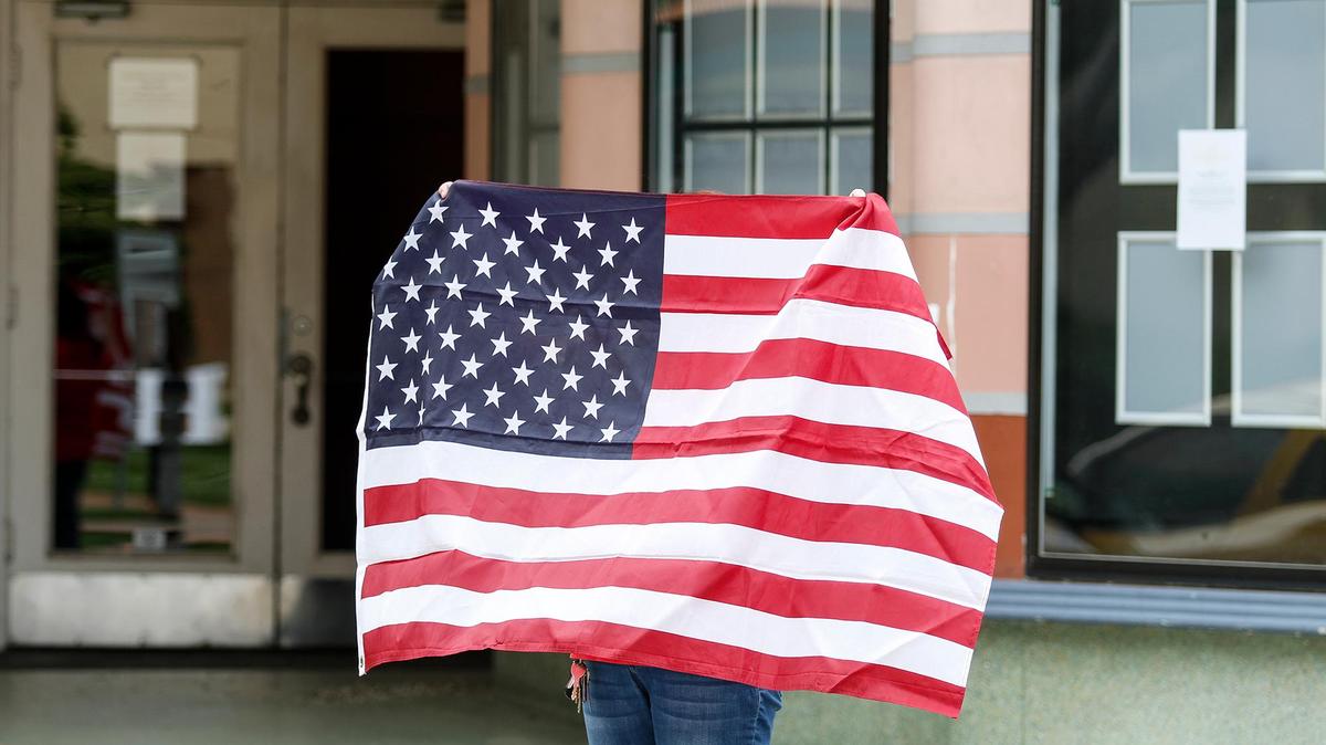 A woman holds up a flag during recent protest calling for the reopening of San Luis Obispo County.