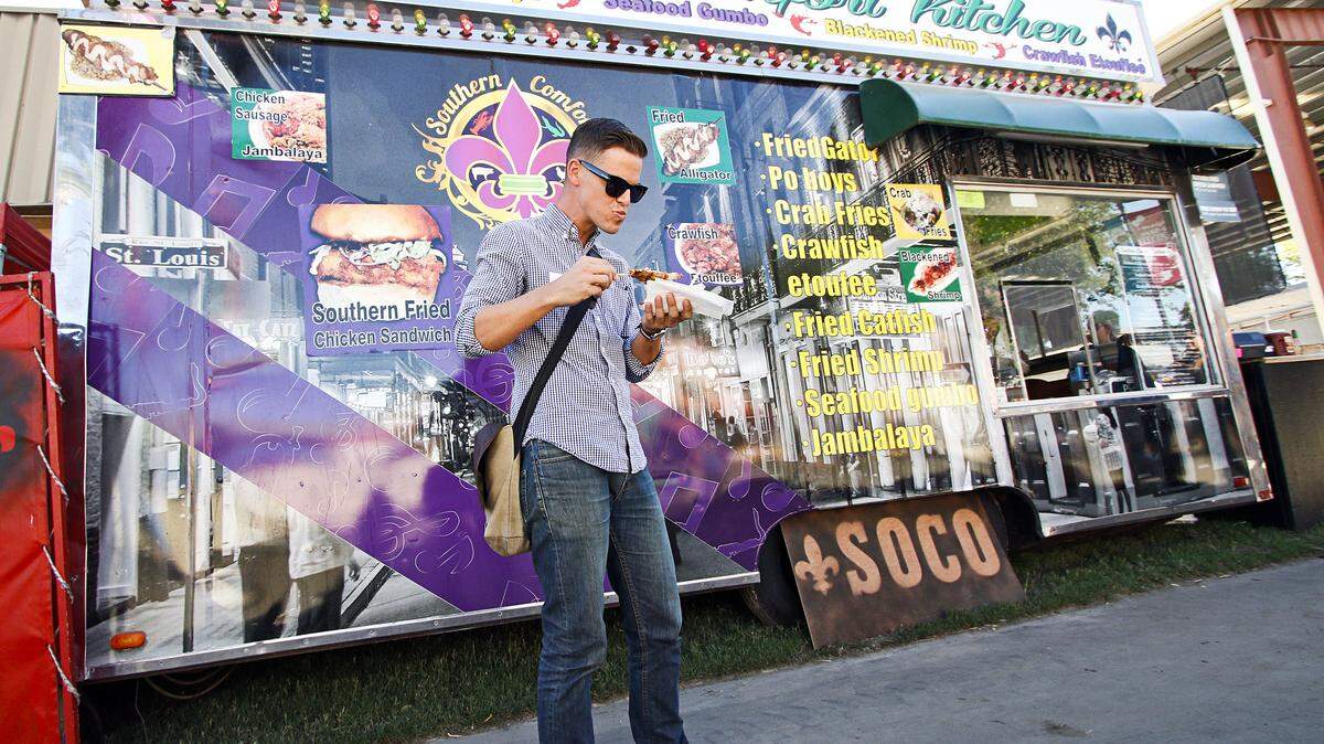 The Tribune's Travis Gibson samples the fried gator bites on a stick from Southern Comfort Kitchen food truck at the California Mid-State Fair.
