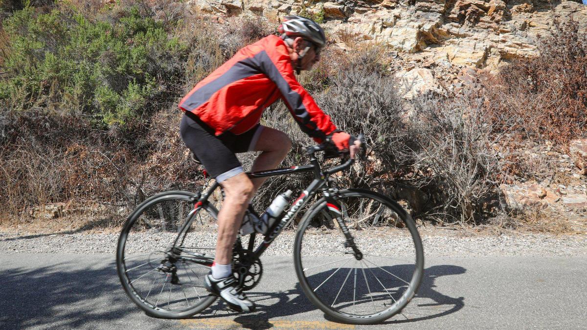 A cyclist glides by fossil-filled Monterey shale on the Bob Jones Trail on Sept. 22, 2023. The rocks were on the ocean floor about 14 million years ago, then uplifted to the surface by plate tectonics, according to a trail interpretive marker. The county wants to complete the trail from Avila Beach to San Luis Obispo but now will likely need to alter the route around at least one property whose owner has refused to sell a sliver of his land.