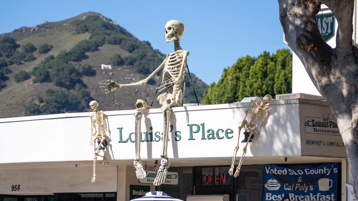 A giant skeleton sits atop Louisa's Place in downtown San Luis Obispo on Thursday, Oct. 23, 2025. Several stores in the downtown area put up spooky decorations for Halloween.