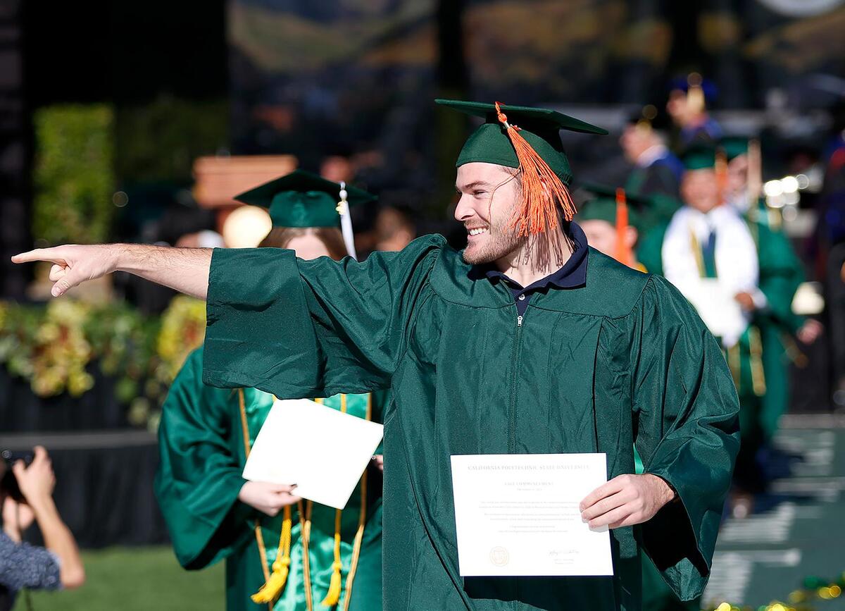 Dylan Prins, a mechanic engineering grad, points to a friend at Cal Poly’s fall commencement on Dec. 11, 2021.