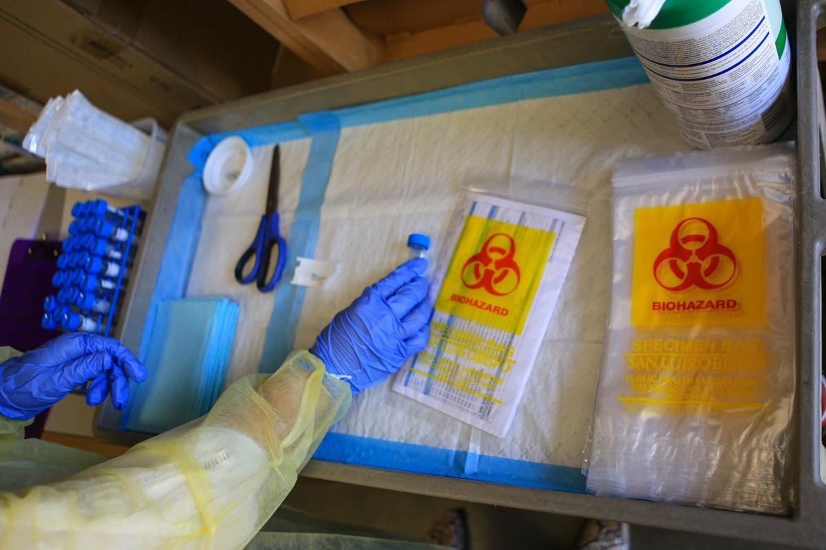 A team of three keep coronavirus testing materials organized so that they can keep up with the average pace of a test scheduled every 10 minutes at the San Luis Obispo County Public Health Department.