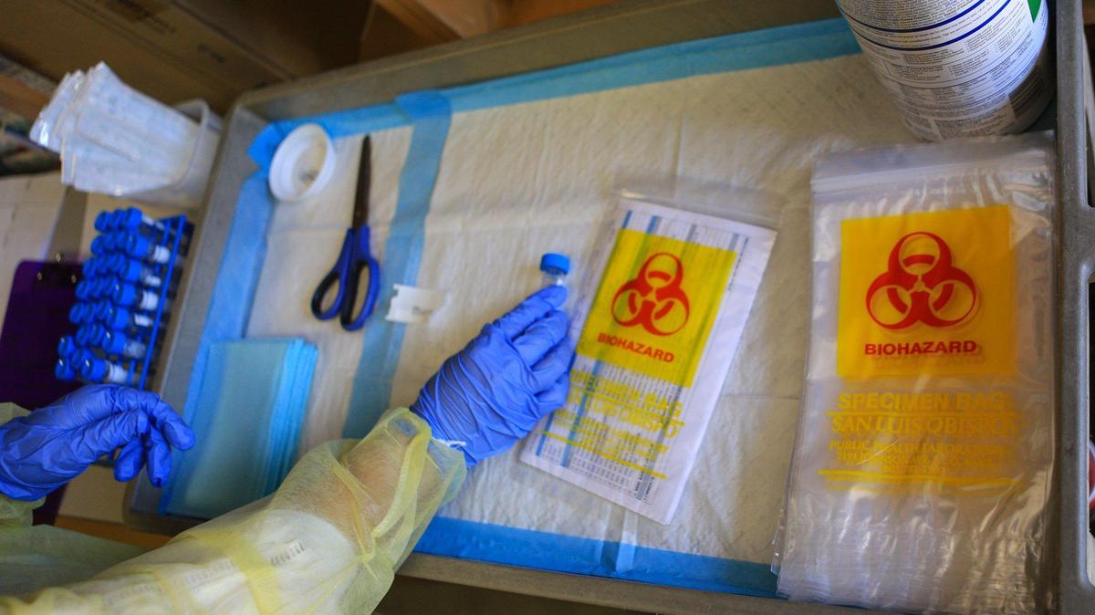 A team of three keep coronavirus testing materials organized so that they can keep up with the average pace of a test scheduled every 10 minutes at the San Luis Obispo County Public Health Department.