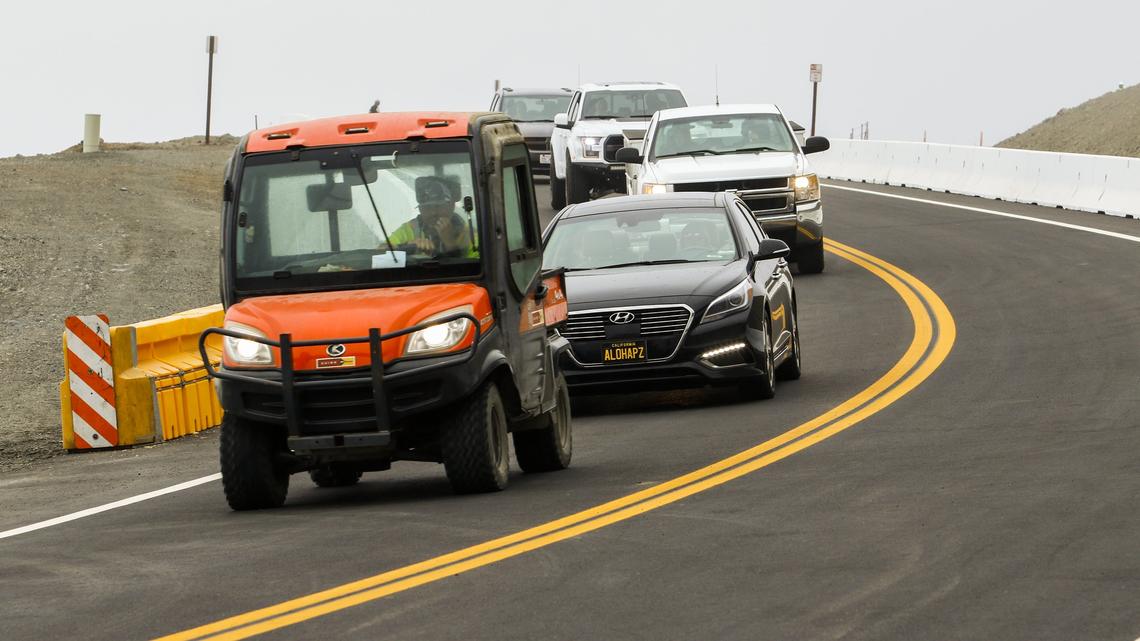 The first cars drive along the newly opened section of Hwy. 1 across the Mud Creek Slide on Wednesday morning.