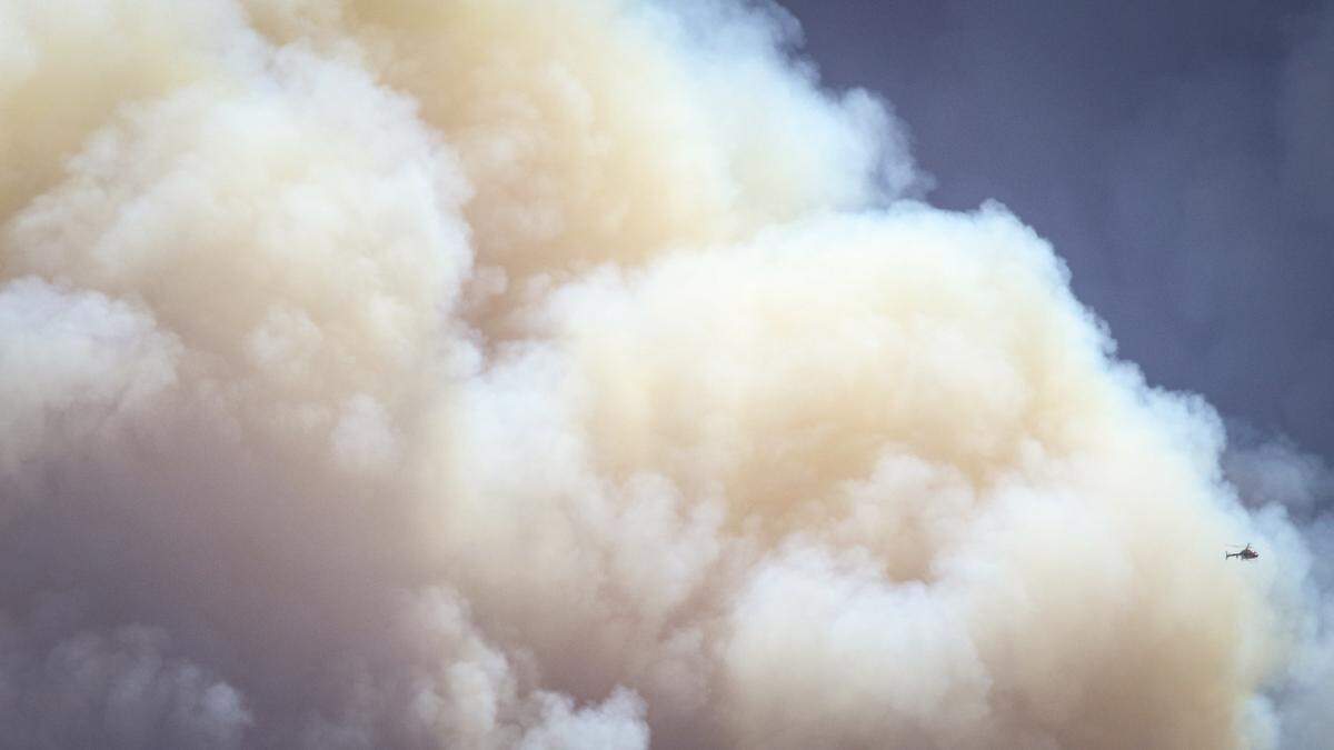 A firefighting helicopter was dwarfed by smoke while battling the Gifford Fire on Aug. 13, 2025.