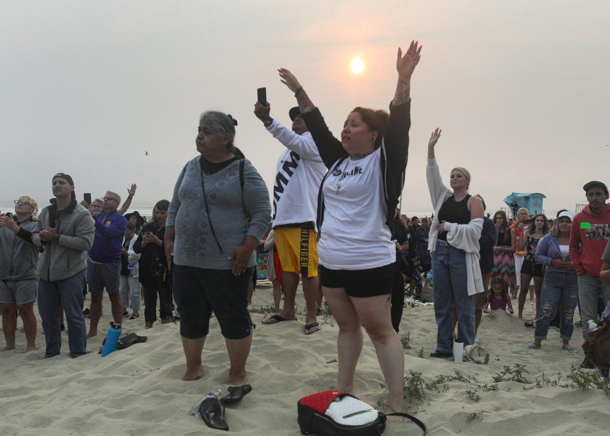 Worshipers raise their arms in prayer during Christian concert in Pismo Beach, part of a multi-city “Let Us Worship” tour.