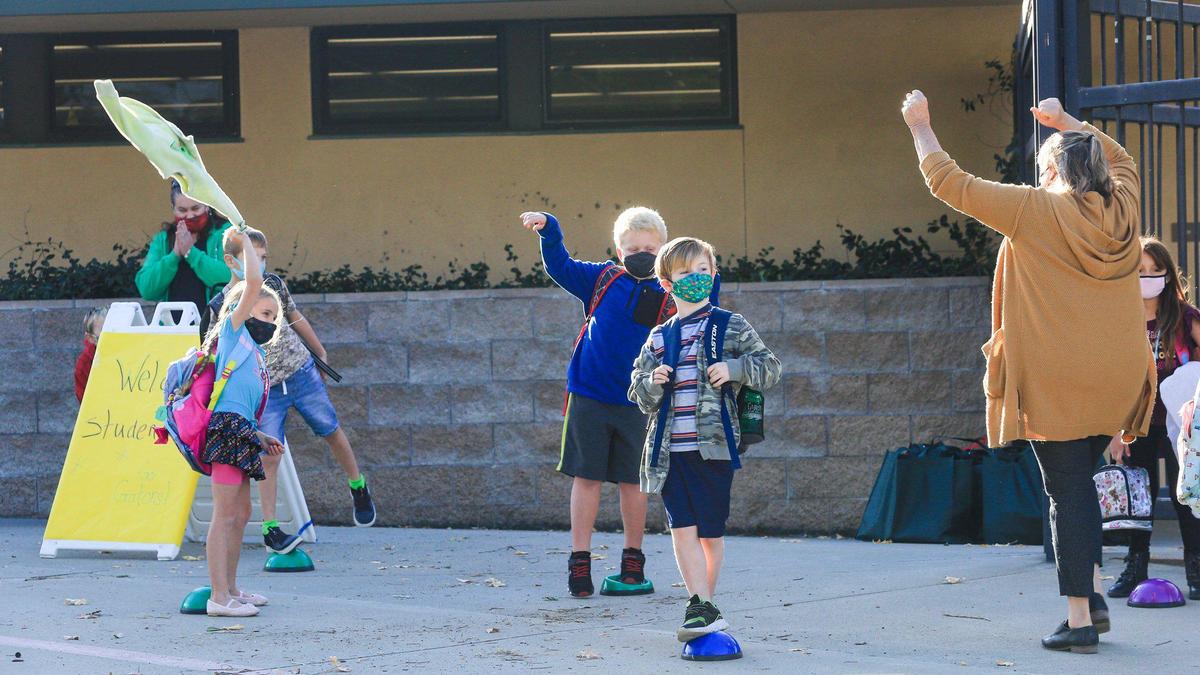 Teacher Ann Platz leads 1st graders in a cheer before heading to class after lining up in distanced spots. Transitional Kindergarten through second grade students attend in-person classes at San Gabriel Elementary School in Atascadero for the first time since March. The students are some of the first in the county at a public school to return to classrooms after the coronavirus pandemic caused schools to shift to virtual-only learning.