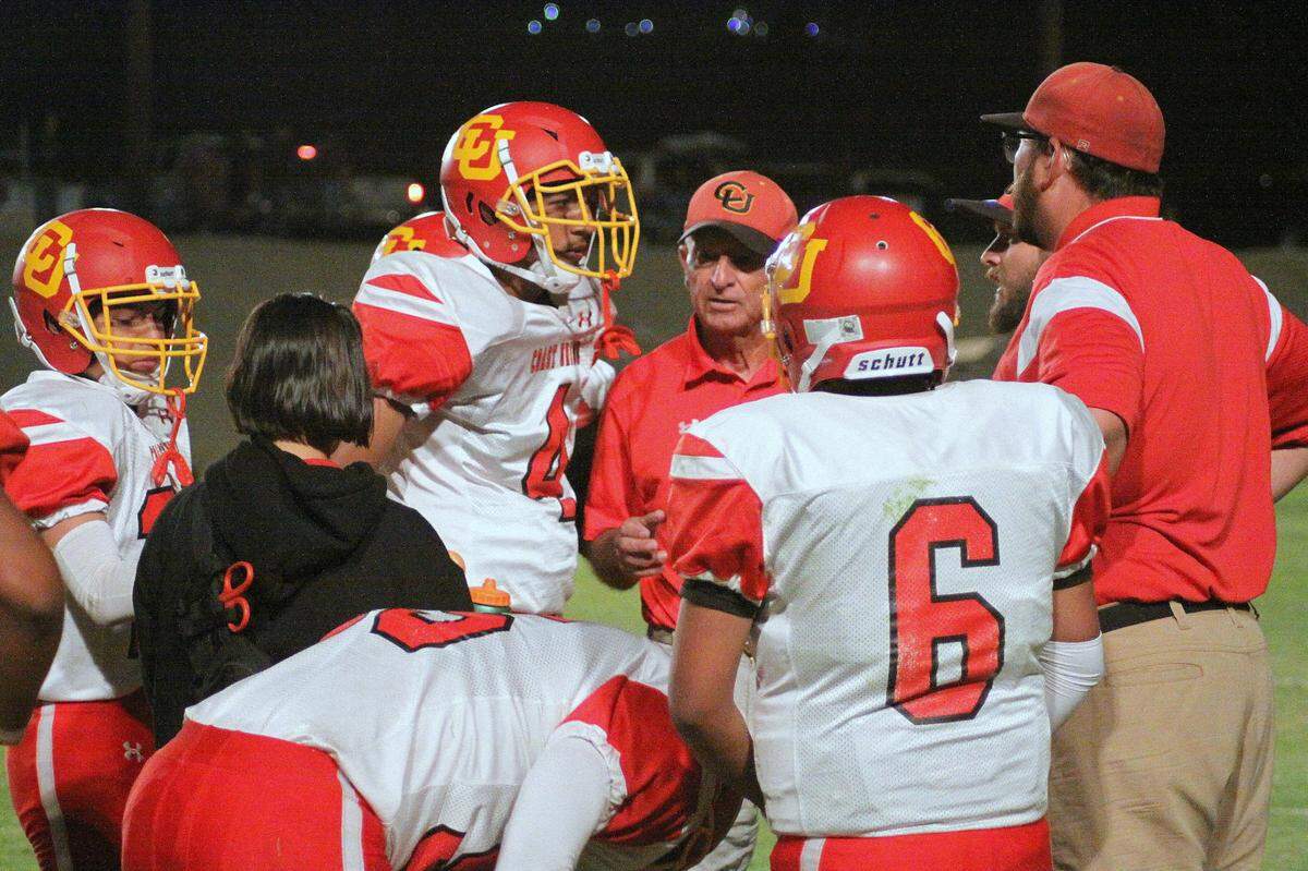 Coast Union High School offensive coordinator Charlie Casale, center in red shirt, and head football coach Andrew Crosby, far right, talk to members of the school’s football team.