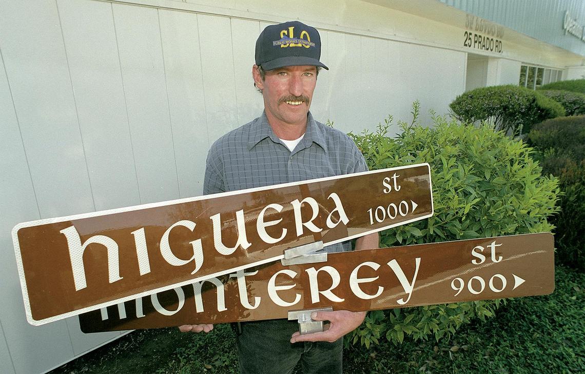 Joe McDermott, city streets supervisor, holds two of the options for the design of San Luis Obispo’s signs. The city has settled on the top version with the white border. Photo originally published April 20, 2000.