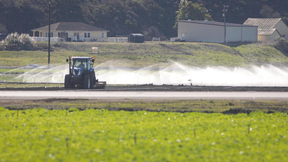 Un tractor labra un campo mientras los aspersores de riego rocían cerca de la Highway 1 y Halcyon Road en Arroyo Grande, el 4 de diciembre de 2023.