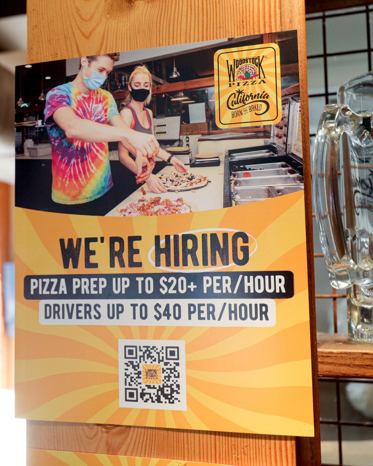 A sign at Woodstock’s Pizza advertises openings starting at $20 an hour on Jan. 12, 2022.