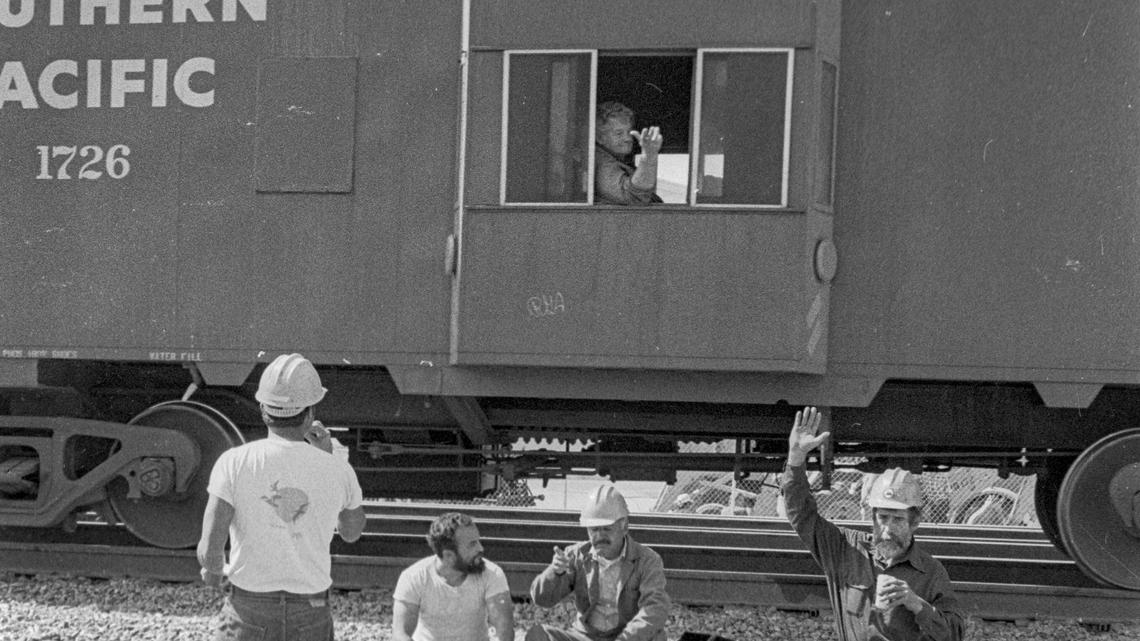 Workers on a lunch break wave to a passing Southern Pacific caboose in San Luis Obispo, Calif. on March 12, 1984.