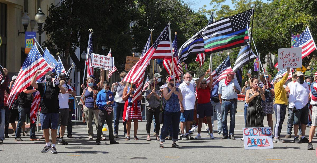 Supporters of District Attorney Dan Dow who want charges filed against activist Tianna Arata wave flags while chanting to disrupt the rally outside the courthouse in San Luis Obispo.