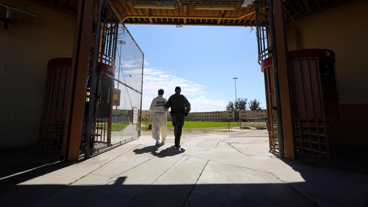 A correctional officer escorts an inmate at California Men’s Colony’s East Facility.
