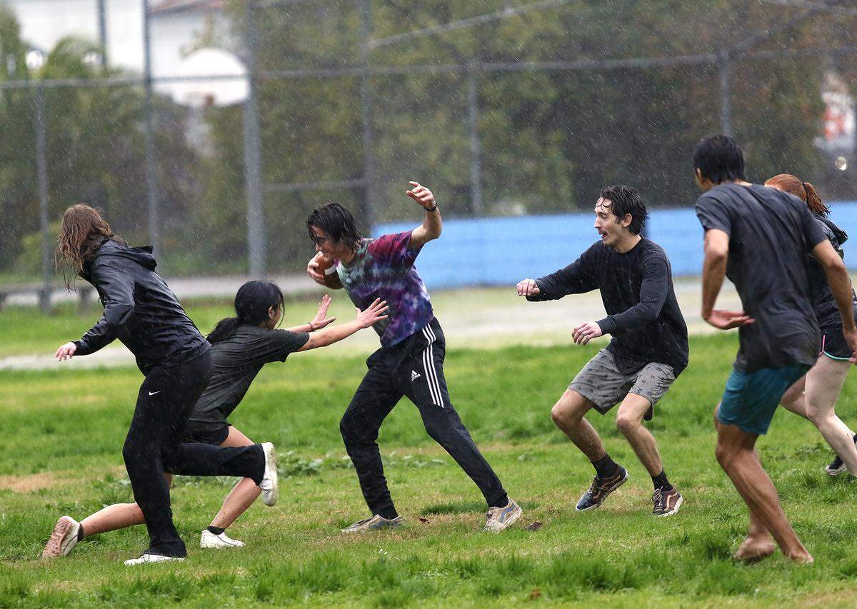 Cal Poly engineering students play football in the rain at the Pacific Beach High School baseball field in San Luis Obispo on Monday, Jan. 9, 2023. The university canceled classes because of the stormy weather.