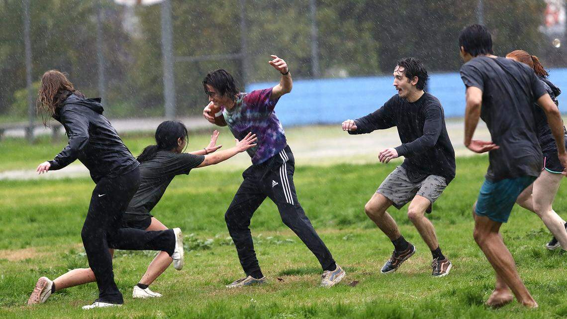 Cal Poly engineering students play football in the rain at the Pacific Beach High School baseball field in San Luis Obispo on Monday, Jan. 9, 2023. The university canceled classes because of the stormy weather.