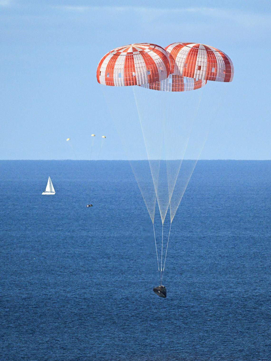 NASA’s Orion capsule descends under its main parachutes over the Pacific Ocean following a successful 10-day Artemis II mission, April 10, 2026.