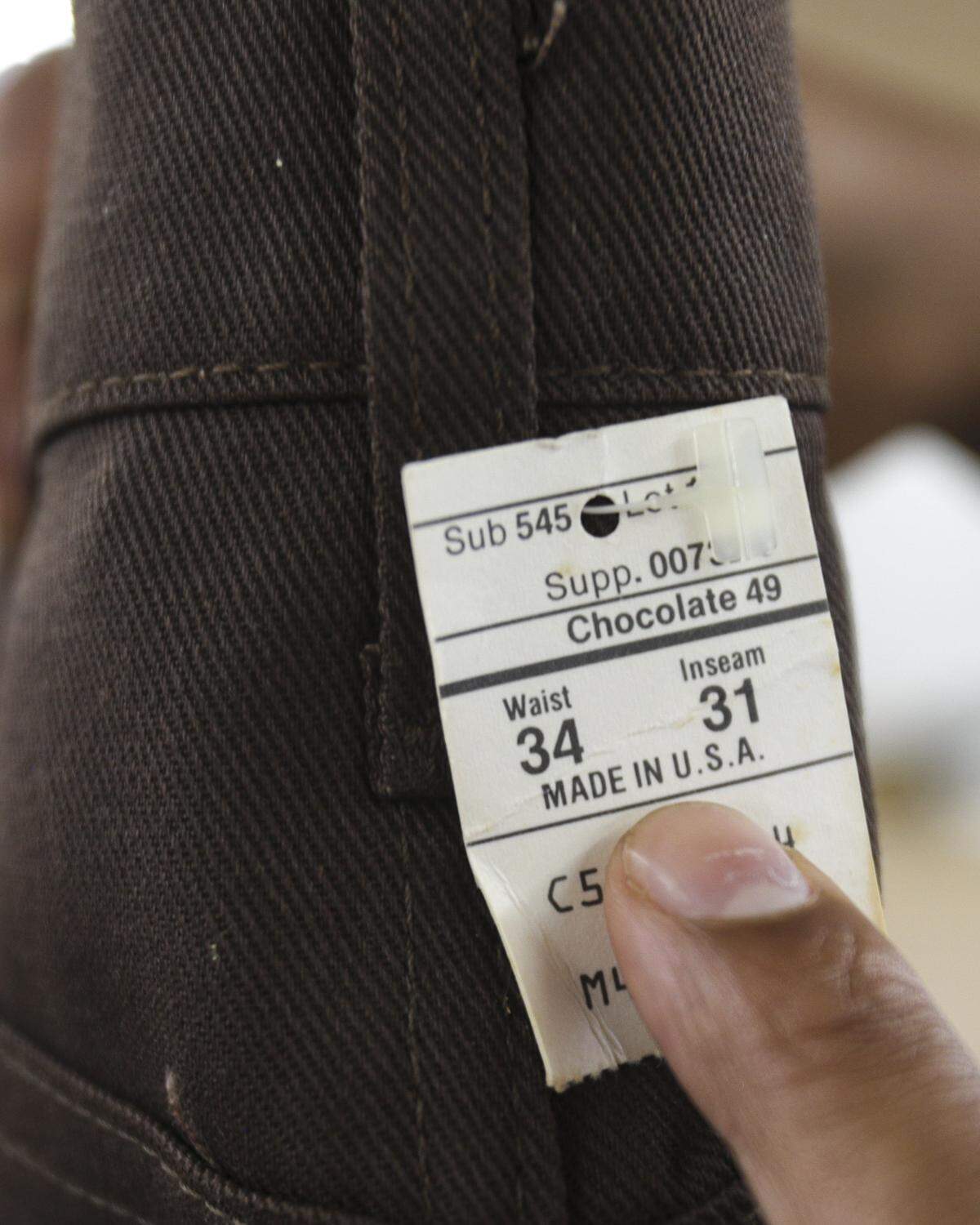 Thrifty Beaches co-owners Adam Kemp shows a tag on an unworn denim piece Sept. 3, 2025.