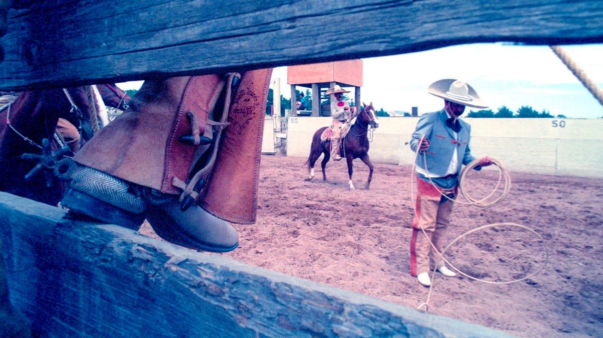 A charro coils his rope as other cowboys sit on the fence and wait their turn. A charreada or Mexican Rodeo was held at Nipomo Regional Park on May 30, 1993.