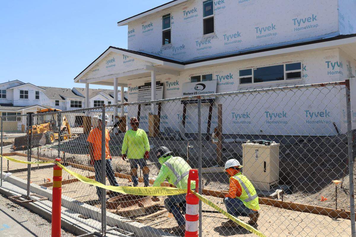 A 70-unit housing development at 10850 El Camino Real in Atascadero has led to disputes with neighbors over slow progress. Construction workers lay a cover for underground utilities at the site in August 2024..
