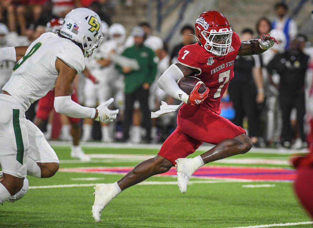 Fresno State’s Jordan Mims, right, takes the ball upfield against Cal Poly in the Bulldogs’ 35-7 win over the Mustangs at Valley Children’s Stadium on Thursday, Sept. 1, 2022.