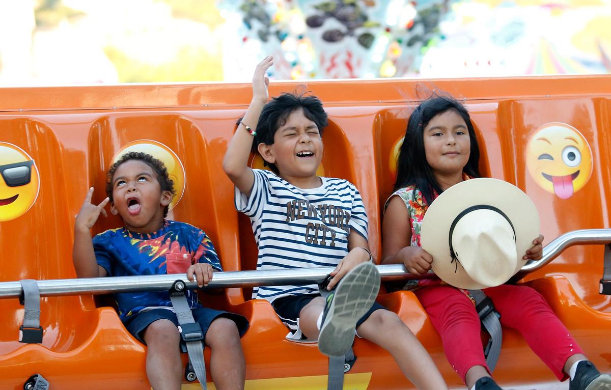 Saint Gildersleeve, 3, left, of Bakersfield makes a face fit to match the emojis on the seats of the Happy Swing ride, on the first day of the California Mid-State Fair in 2021. The fair kicks off Wednesday, July 17, 2024, in Paso Robles.