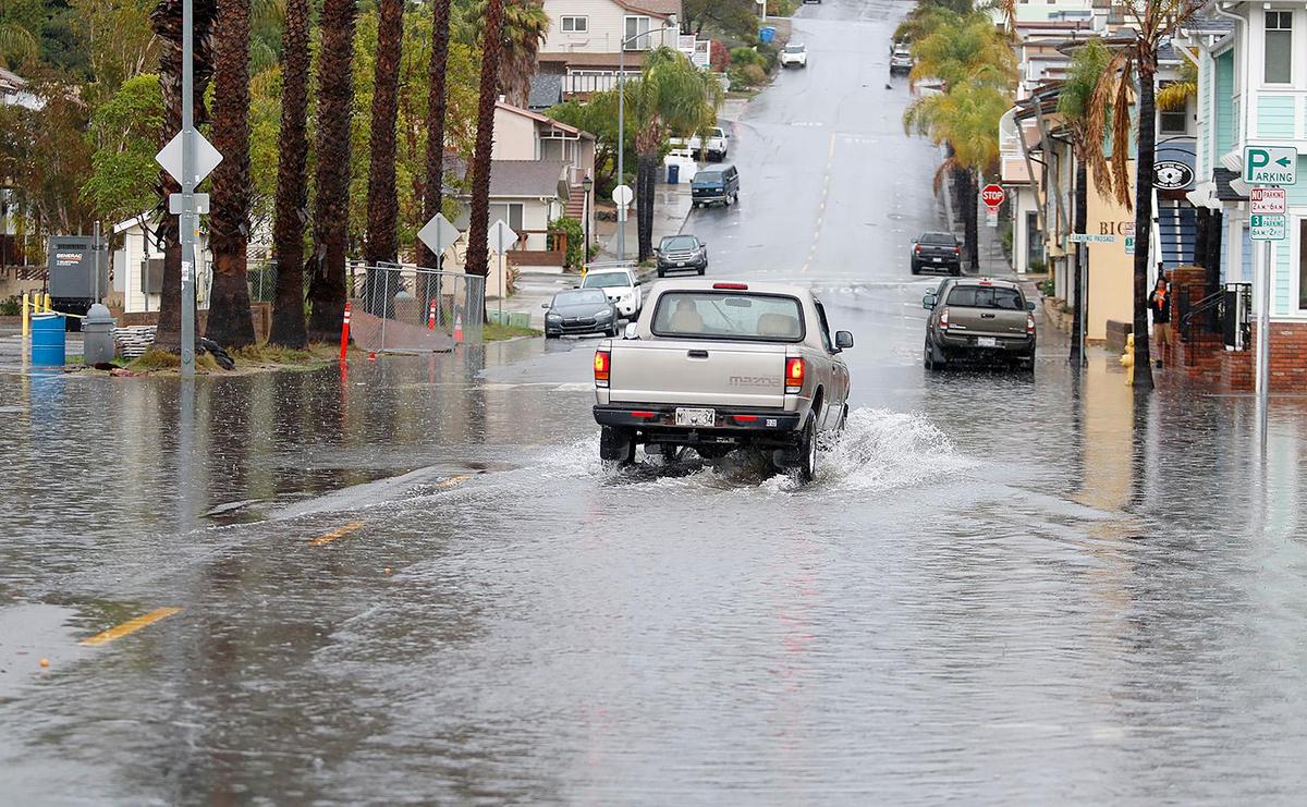 A pickup truck drives through a flooded intersection in Avila Beach as a second day of rain drenched the county on Tuesday, Dec. 14, 2021.