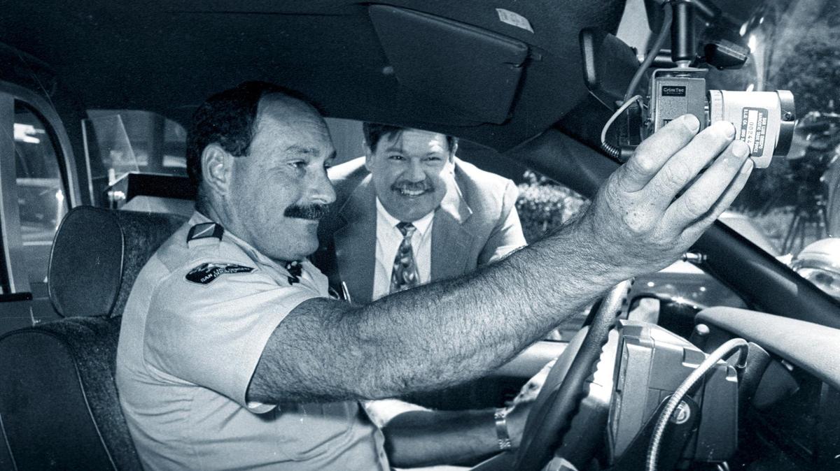 San Luis Obispo County Sheriff’s Office Capt. Bill Crout watches as Deputy Jason Nefores tests a tiny new crime-fighting video camera mounted to a patrol car windshield in August 1991.