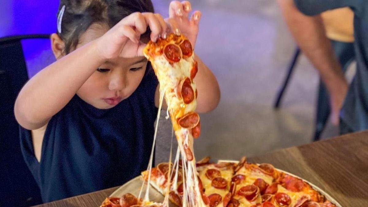 A child grabs a slice of pepperoni at Mountain Mike’s Pizza. The pizzeria opened a location in Atascadero in April 2022.