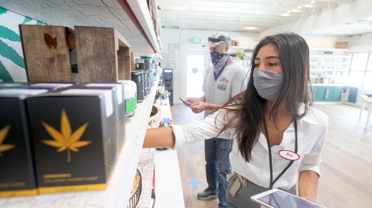 Ana Jahrstorfer assists a customer with a cannabis purchase at Megan’s Organic Market in San Luis Obispo in August 2020.