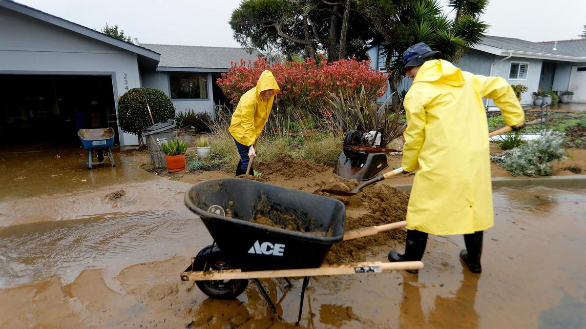 Los Osos resident Bruce Hendry joined the cleanup effort with his son, Sawyer, and rain splashed on the pair as they shoveled mud out of Kay Blaney’s driveway on Vista Court on Tuesday, Jan. 10, 2023. A water retention basin failed and sent a torrent of floodwater pouring down onto the neighborhood from the hillside above.