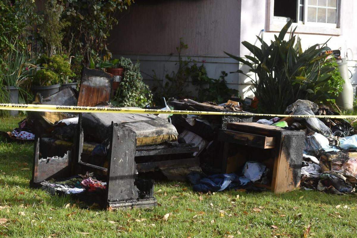 A pile of charred items sits on the lawn at a Tanglewood house after a Sunday night fire that killed two women, injured a man and left multiple people without a home.