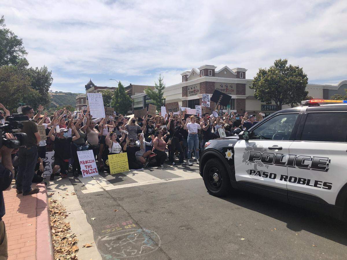 Protesters stand and chant in front of a police line blocking Pine Street in downtown Paso Robles on Tuesday, June 2, 2020.